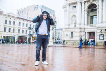 man walk under rain covered by his jacket. spring rainy weather