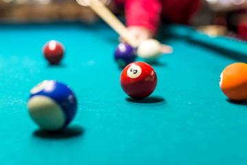 Close-up of someone aiming the billiard ball with cue .