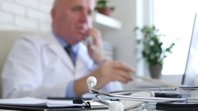 Doctor Talking on Telephone in Blurred Image and a Stethoscope in Focus