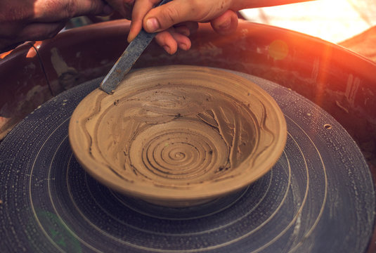 hand maid, molding from clay, making dishes at sunset.