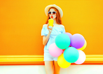 young woman holds an air colorful balloons on a orange background