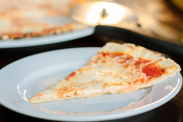 Slice of four cheese pizza at white ceramic plate.