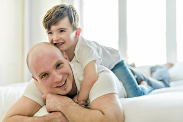 Happy father and son having fun together on a bed