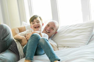Happy father and son having fun together on a bed