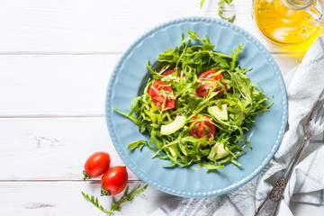 Healthy vegan salad from arugula, avocado and tomatoes.