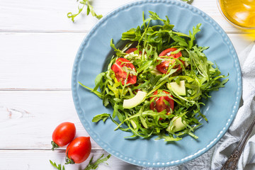 Healthy vegan salad from arugula, avocado and tomatoes.