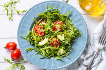 Healthy vegan salad from arugula, avocado and tomatoes.