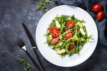 Green salad from arugula, avocado and tomatoes.