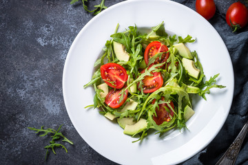 Green salad from arugula, avocado and tomatoes.