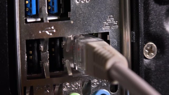 A cable is plugged into a port on the rear of a desktop computer - closeup