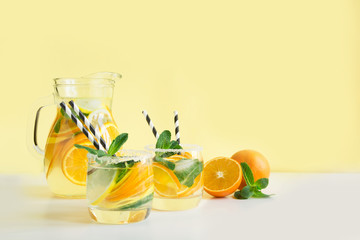 Fresh summer lemonade with citrus, orange and mint on yellow background.