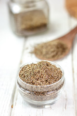 Cumin or caraway spice in a glass jar over white wooden background.