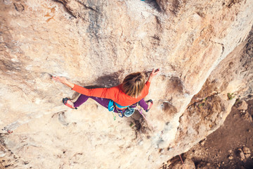 A woman climbs the rock.