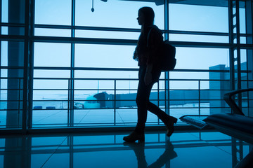 Fototapeta na wymiar Silhouette of girl walking on airport terminal