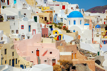 Colorful houses and churches with blue domes in Oia village on Santorini island, Greece