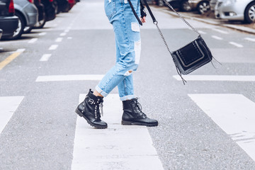 fashion blogger outfit details. fashionable woman wearing ripped vintage denim jeans, suede jacket, black biker boots -ankle shoes and black trendy handbag. detail of a perfect fall fashion outfit. 