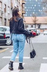 Fototapeta na wymiar fashion blogger outfit details. fashionable woman wearing ripped vintage denim jeans, suede jacket, black biker boots -ankle shoes and black trendy handbag. detail of a perfect fall fashion outfit. 