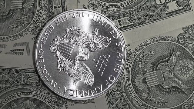silver dollar coin and one dollar bills close up