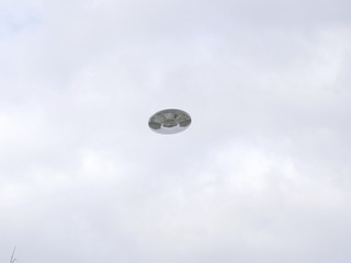 UFO Sighting, flying saucer in the cloudy sky, reflective metal aircraft