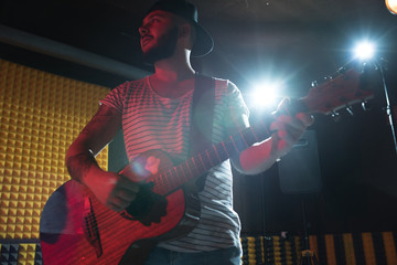 Obraz premium Low angle portrait of modern musician playing guitar in record studio, copy space