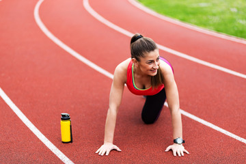 Shot of young woman doing push-ups at stadium