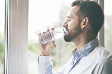 Obraz na płótnie Canvas bearded man drinking bottle of water