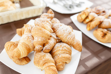 Fresh croissants on white plate. French traditional pastry. Breakfast in hotel smorgasbord.