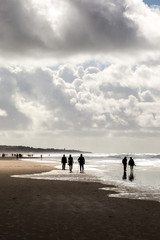 People in the beach under a beautiful cloudy sky