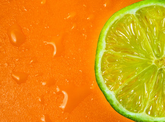 Fototapeta na wymiar Sliced lime citrus on orange plastic cutting board isolated macro close up with water drops