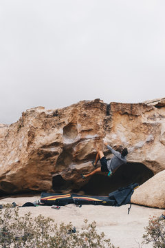 Man Bouldering outside with a heel hook