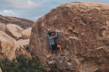 Young Man Bouldering outside in Joshua Tree