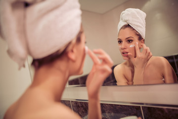 Woman applying facial cream on her face