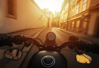 POV shot of man riding on a motorcycle. Hands of motorcyclist on a streets of Prague historical centre, Czech republic.