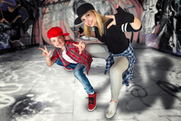 Fototapeta na wymiar Mother and son dance hip-hop.Urban lifestyle. Hip-hop generation.Graffiti on the walls.