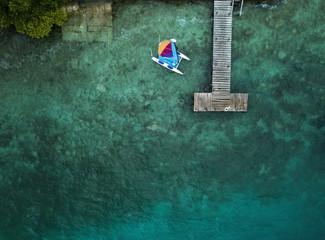 Catamaran, wooden pier and blue water from above