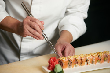 Male chef cooks preparing sushi in the restaurant kitchen. Chef cooking Classic Japanese sushi, served on a stone plate