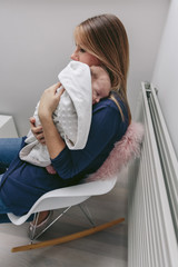 Mother hugging her sleeping baby girl wrapped in a blanket