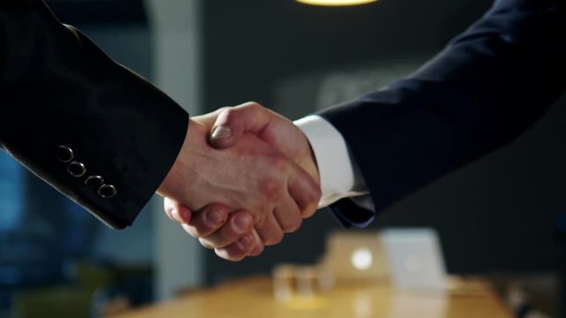 Businessmen shaking hands in office.