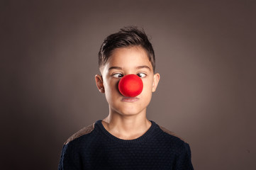 kid with a clown nose on a gray background