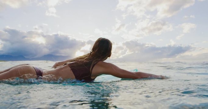 Beautiful young woman going surfing at sunset, active lifestyle, slow motion underwater view