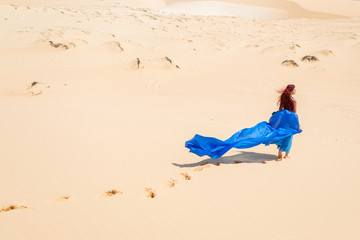 Fototapeta na wymiar Sensual woman in blue from back on sands