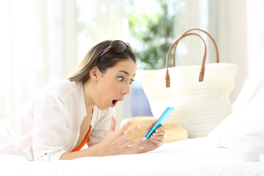 Amazed woman using a phone in summer vacations