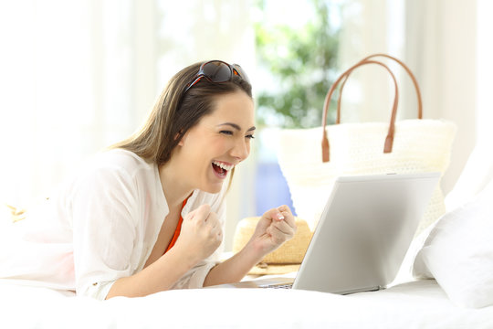 Excited woman using a laptop in vacations