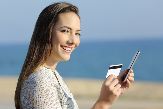 Girl holding a credit card and phone looking at camera