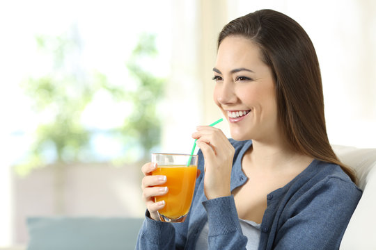 Happy girl holding an orange juice glass at home