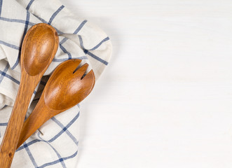 Wooden spoons with blue and white kitchen towel on white wooden table