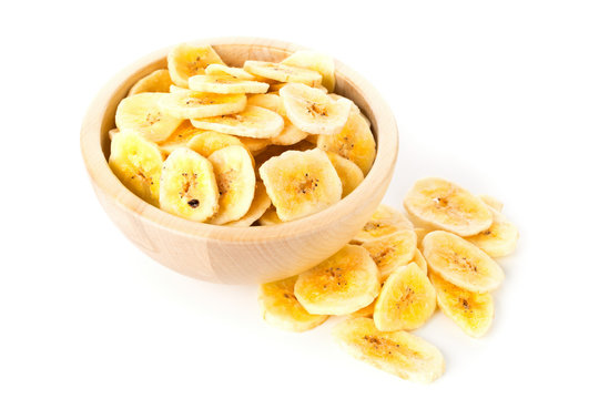 Heap of dried banana chips snack in wooden bowl over white