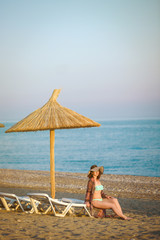 Girl sitting on a beach, under an beach umbrella