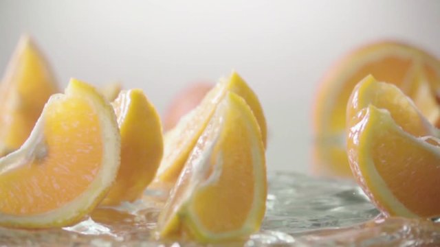 Orange splits into halves on water. Slow motion shot