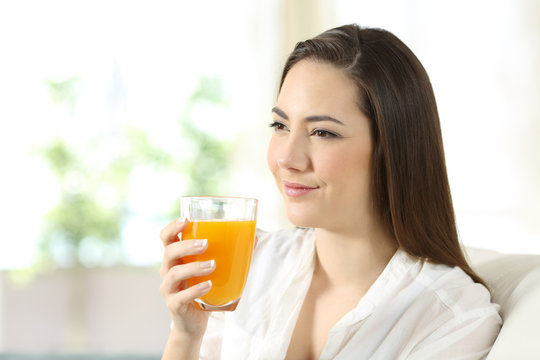 Woman holding a glass of orange juice at home